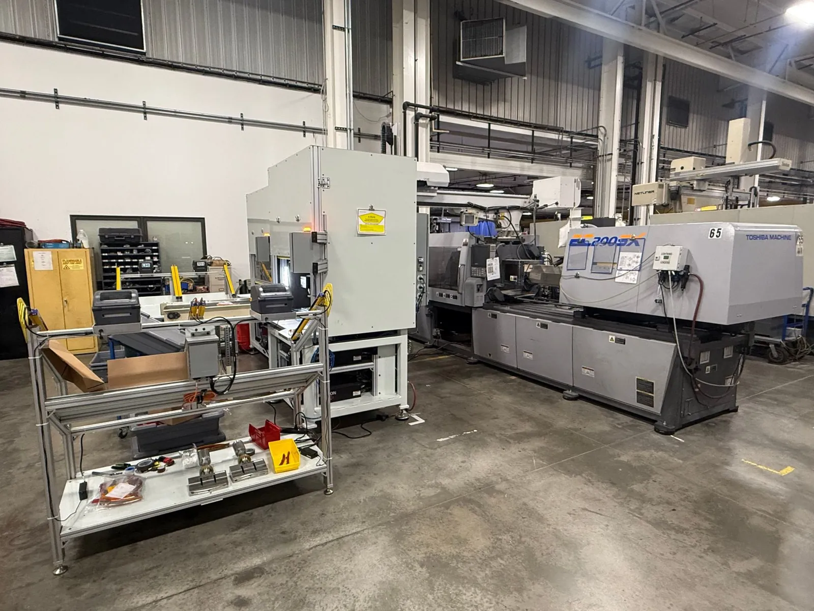 Automated assembly cell with label printers beside a Toshiba injection molding press
